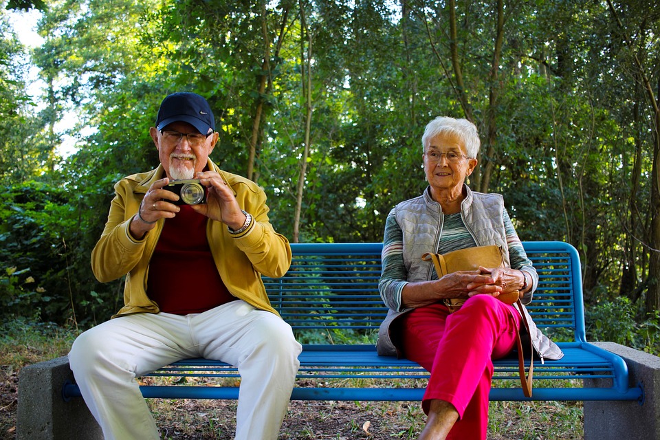 Two older adults sitting on a park bench. 