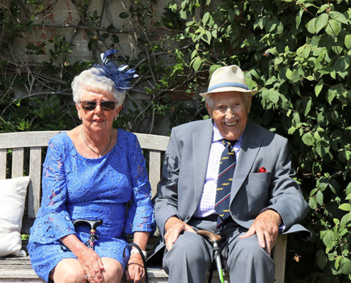 Two older adults dressed up and smiling.