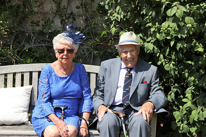 Two older adults dressed up and smiling.
