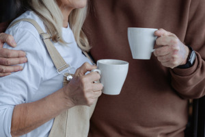 A photo of two people holding cups of coffee with their arms around each other