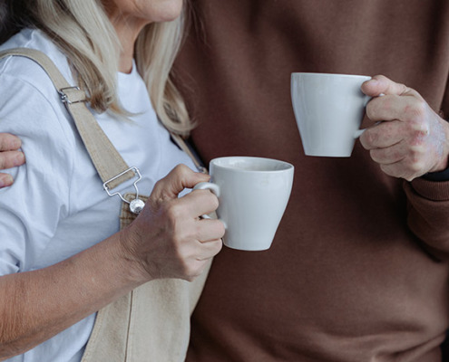 A photo of two people holding cups of coffee with their arms around each other